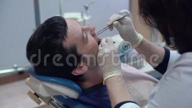 一位戴着无菌口罩和衣服的牙医用<strong>医疗器械</strong>在病人口`做手术
